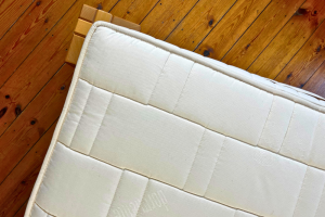 ariel view of a natural latex mattress with an undyed organic cotton quilted cover on a polished wooden floor