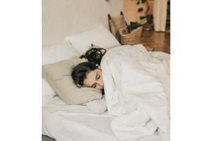 A woman is sleeping under a white duvet 
