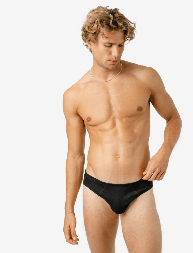 A man is wearing navy blue organic cotton briefs and smiling 