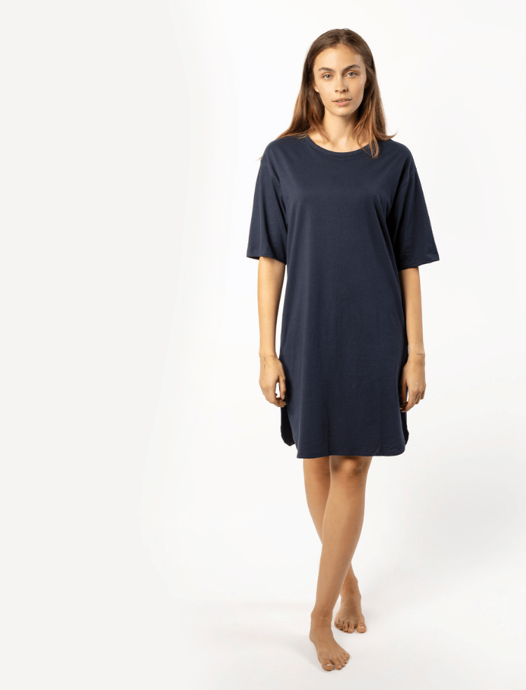 A woman is wearing a pink with white stripe organic cotton nightshirt 