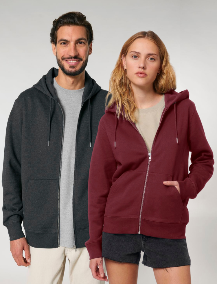 A man wearing an organic burgundy zip hoodie, and a woman wearing an organic dark heather grey zip up hoodie. 