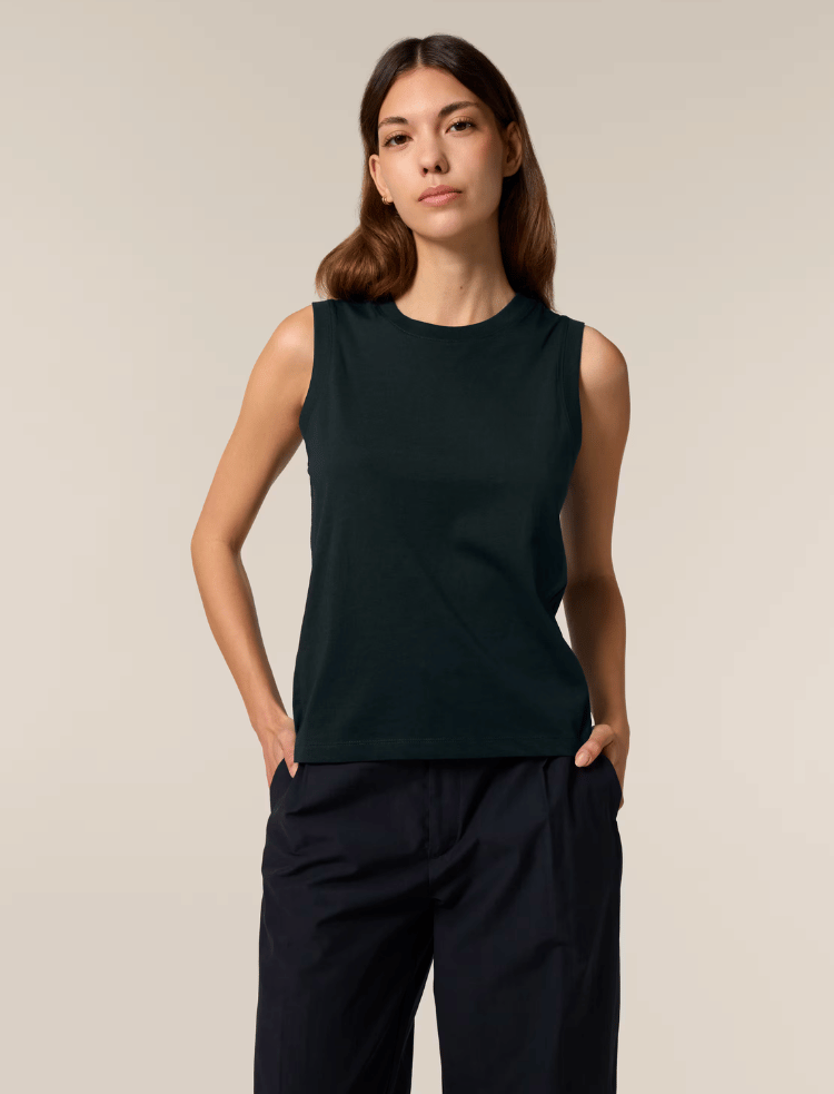 a woman is wearing a white organic cotton sleeveless tank top and smiling 