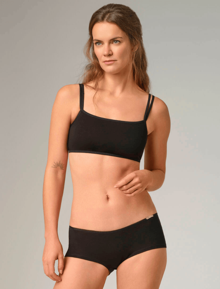 a woman wearing a black organic cotton bralette and black organic cotton hipster style knickers