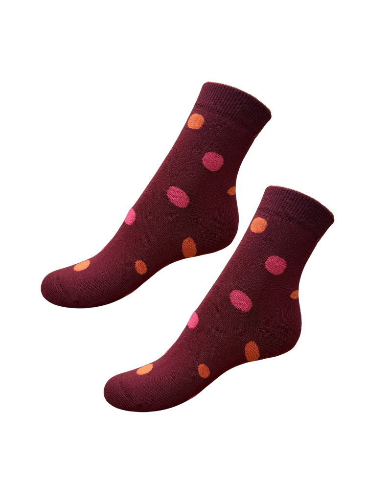 a pair of burgundy organic cotton socks with orange and pink spots lying flat on a white background 
