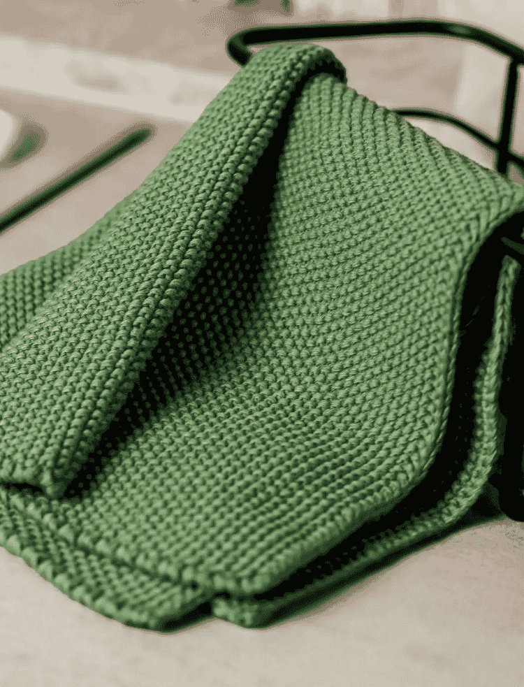 green organic cotton dishcloth draped over a container 