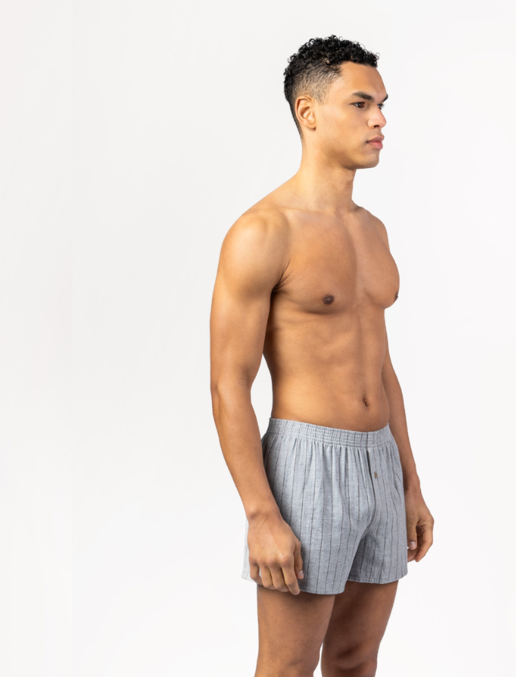 A man wearing burgundy organic cotton flannel boxer shorts with a light grey check pattern 