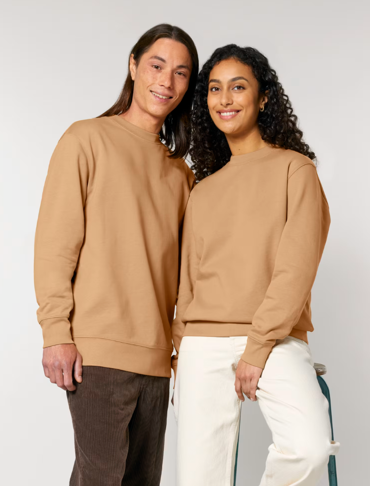 A man and a woman are wearing latte coloured organic cotton sweaters and smiling 