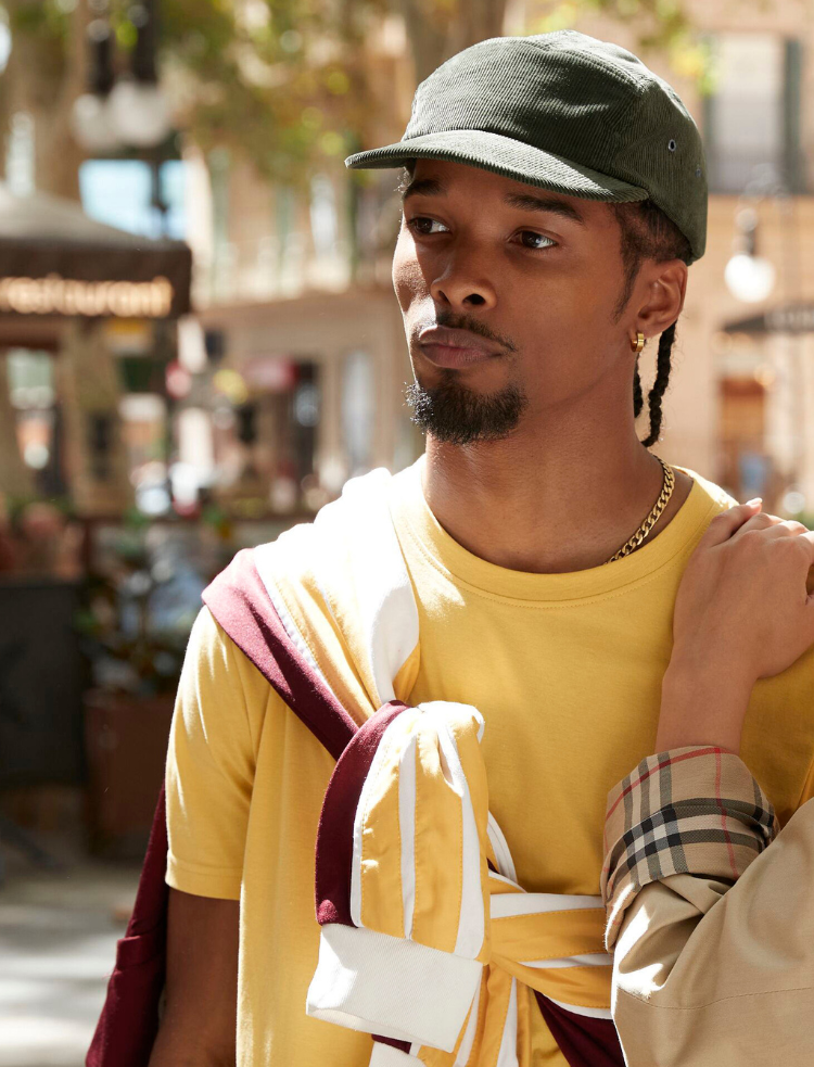 A man wearing a green organic corduroy cap and a yellow t-shirt