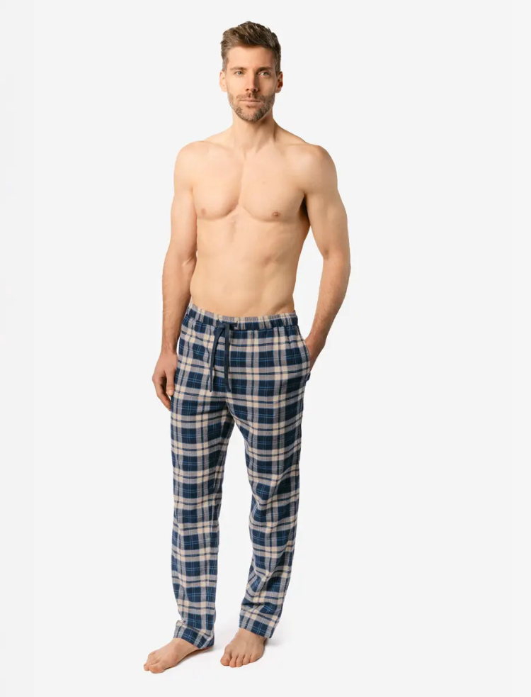 A man is wearing blue check organic cotton PJ trousers and a long sleeve white t-shirt