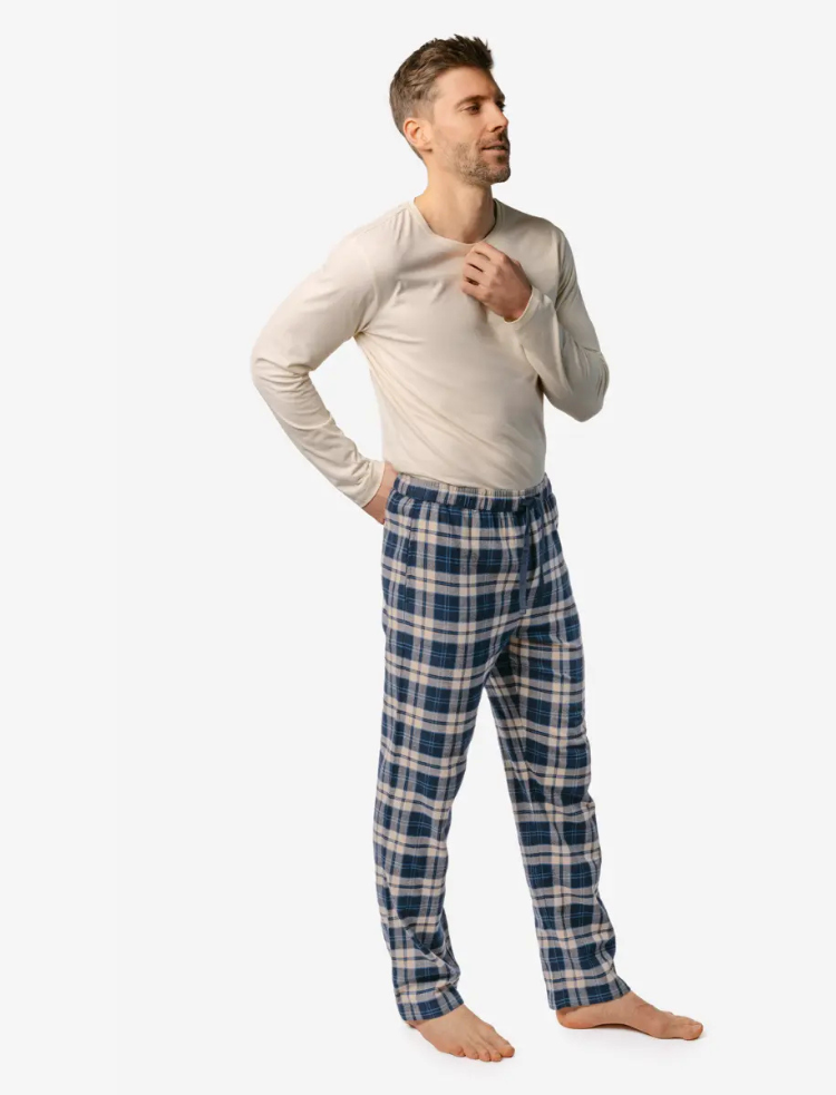 A man is wearing blue check organic cotton PJ trousers and a long sleeve white t-shirt