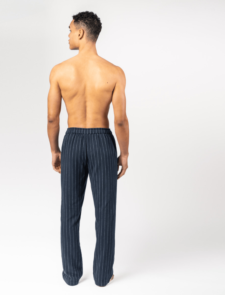 A man wearing a white t-shirt and organic cotton navy pinstripe pyjama bottoms 