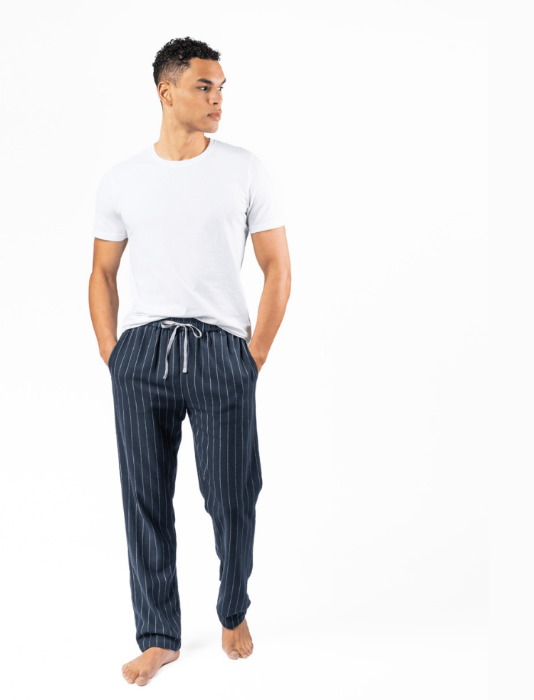 A man wearing a white t-shirt and organic cotton navy pinstripe pyjama bottoms 