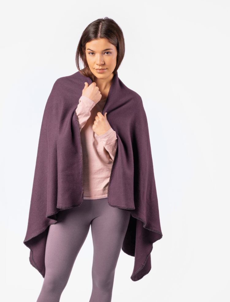 A woman with long dark hair draped in a plum coloured fleece blanket