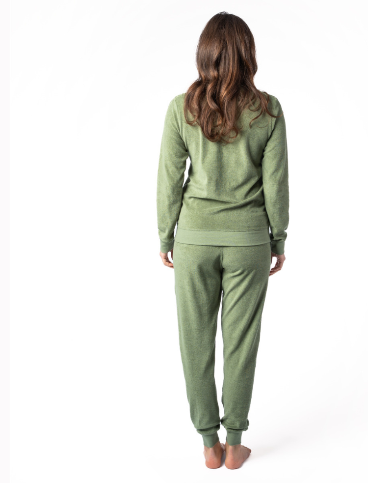 A woman wearing fern green organic cotton terry pyjamas with bare feet