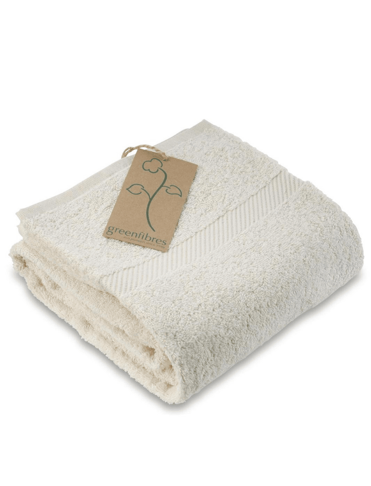 a folded up organic cotton shower towel, in a natural and undyed colour, with a cardboard swing tag printed with the Greenfibres logo 