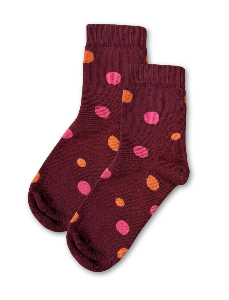 a pair of burgundy organic cotton socks with orange and pink spots lying flat on a white background 