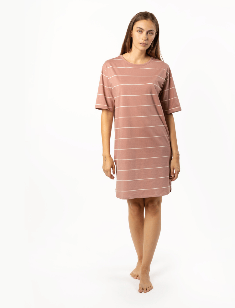 A woman is wearing a pink with white stripe organic cotton nightshirt 