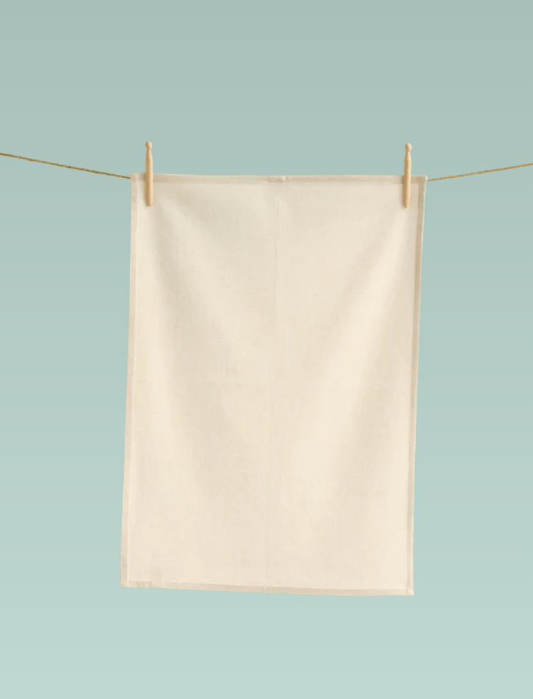 two white and one natural organic cotton tea towel hanging from a washing line with wooden pegs