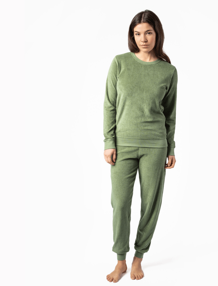 A woman wearing fern green organic cotton terry pyjamas with bare feet