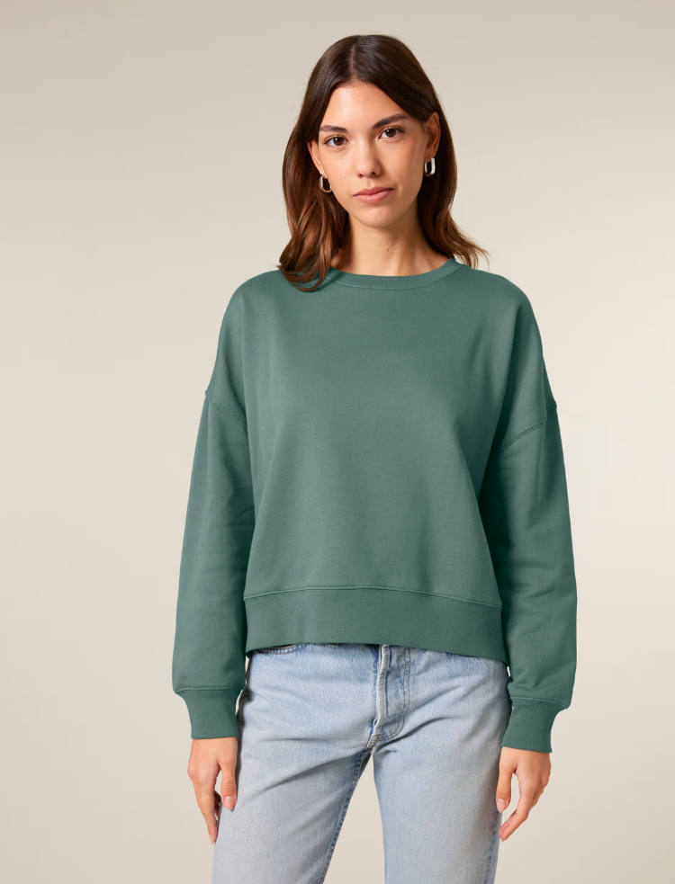 A woman wearing a black organic cotton sweater and jeans 