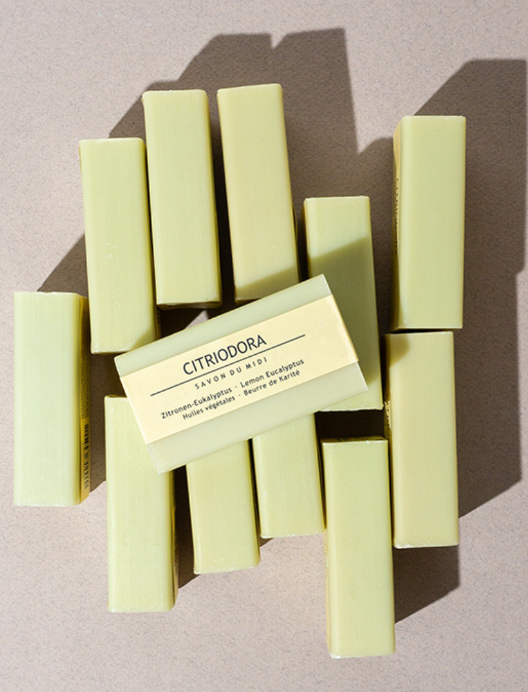 organic shea butter soap bar in cinnamon orange on a blue background with cinnamon sticks and orange slices