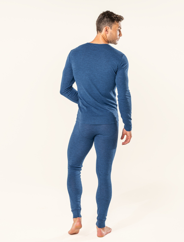 a mean wearing organic thermal base layers holding a cup of tea in the doorway of a wooden cabin 