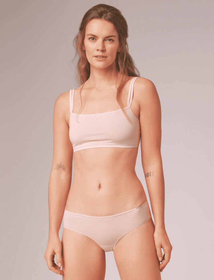 a lady with long hair wearing soft pink organic cotton bralette and knickers 