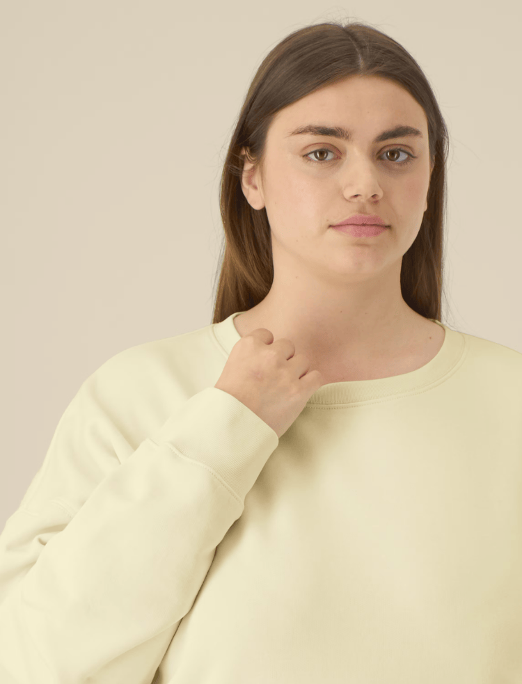 a woman is wearing an organic cotton sweater over a poloneck 