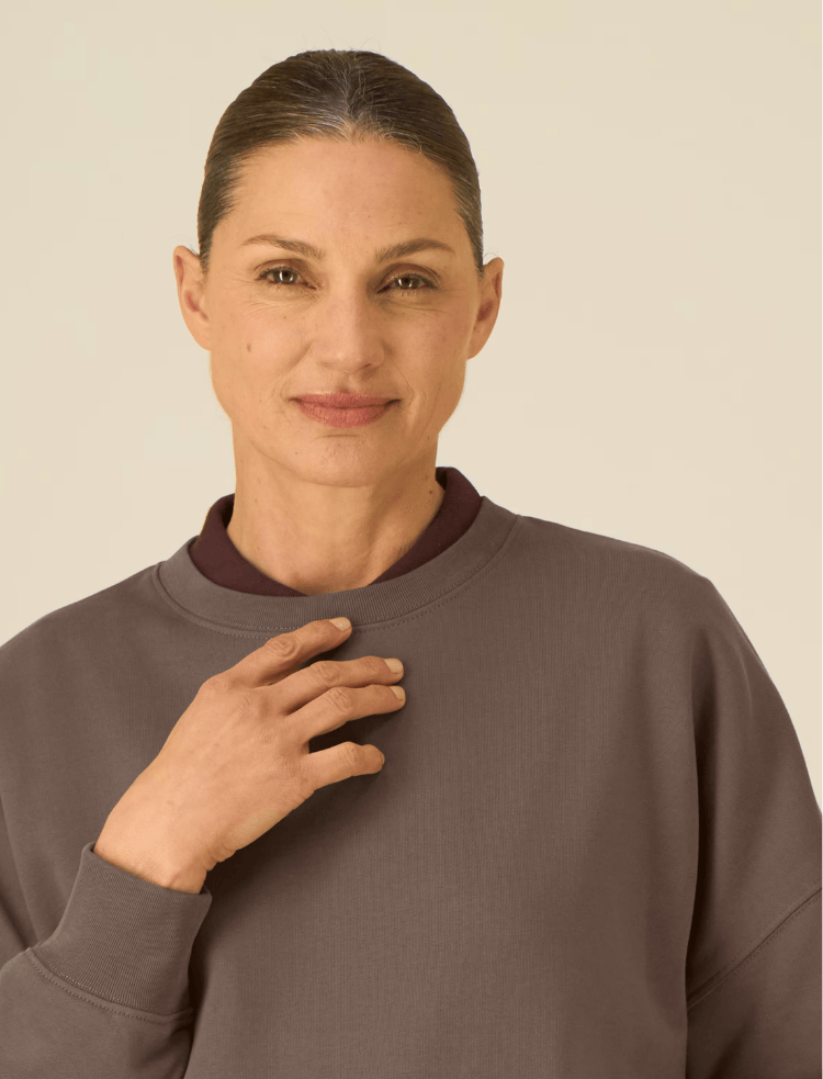a woman is wearing an organic cotton sweater over a poloneck 