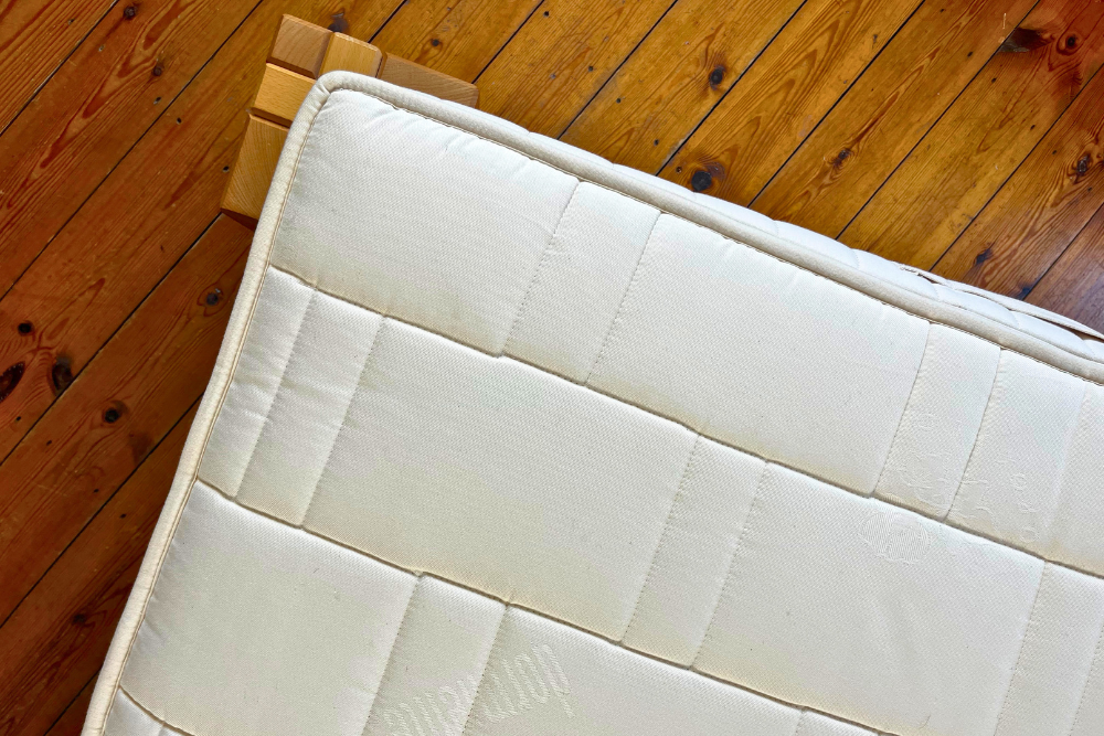 ariel view of a natural latex mattress with an undyed organic cotton quilted cover on a polished wooden floor