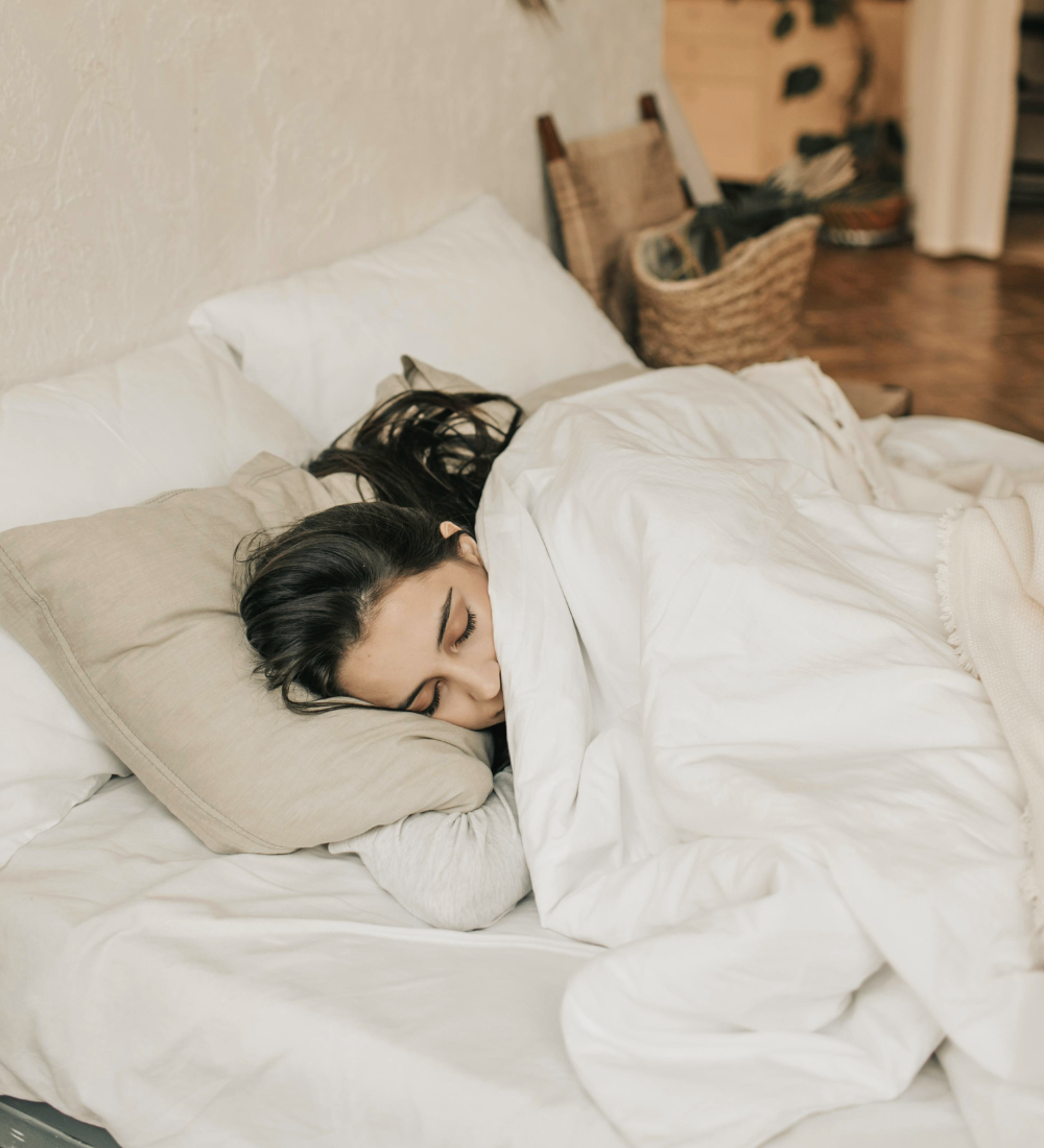 A woman is sleeping under a white duvet 