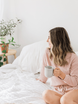 a woman drinking coffee in bed 