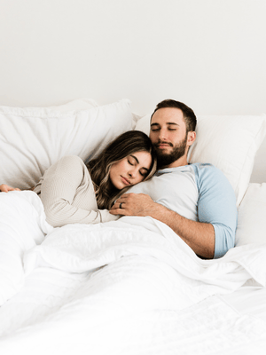 a couple sleeping peacefully in bed in organic cotton bedding