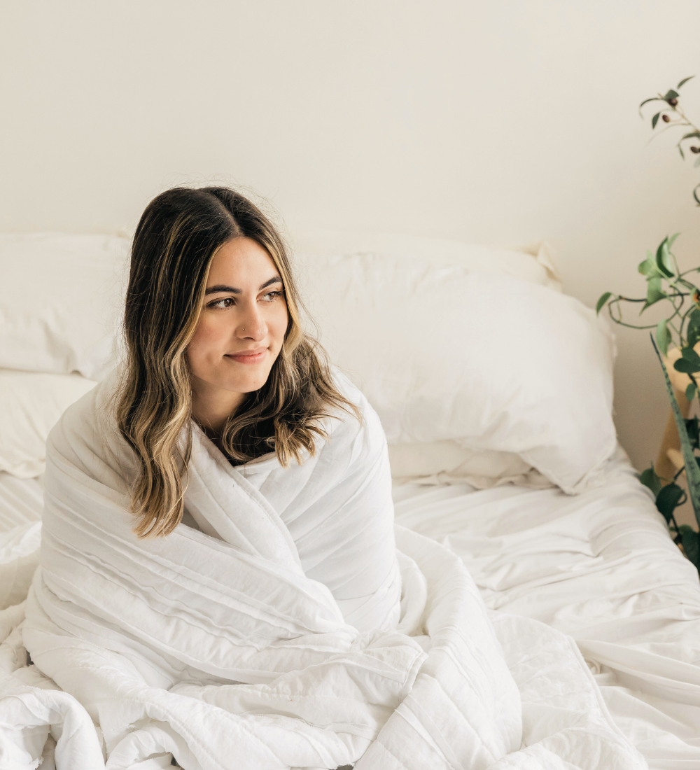 a woman wrapped up in a white duvet and smiling