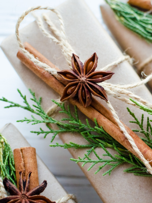 a gift wrapped in brown paper and string with dried orange and cinnamon stick