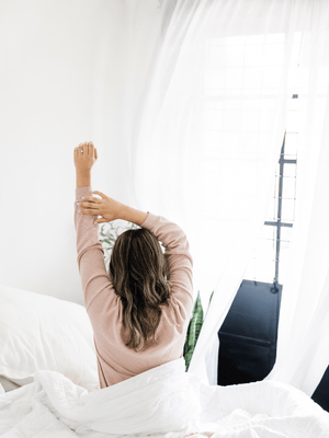 a woman enjoying tea in bed with organic bed linen