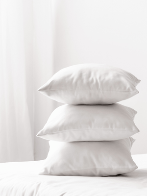 a stack of 3 crisp white pillow cases on a bed